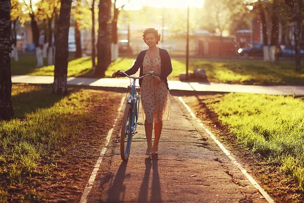 Девушка с велосипедом на закате — стоковое фото