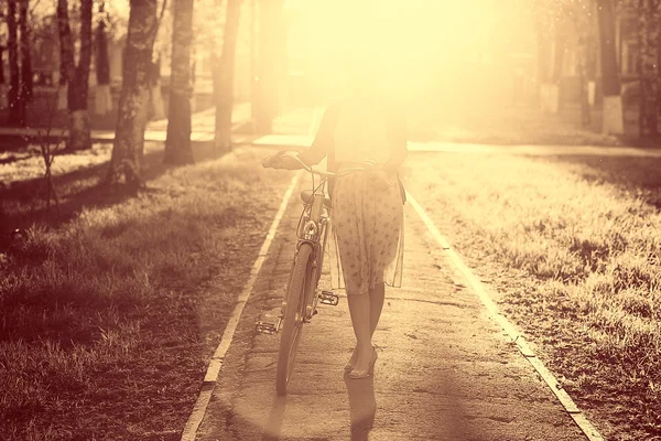 Дівчина з велосипедом на заході сонця — стокове фото