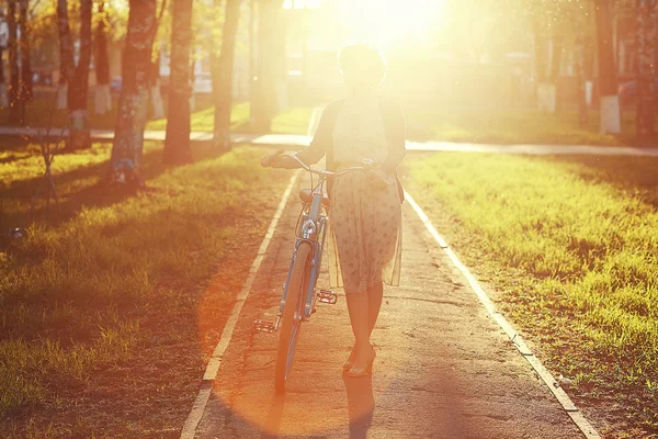Menina com bicicleta ao pôr do sol — Fotografia de Stock