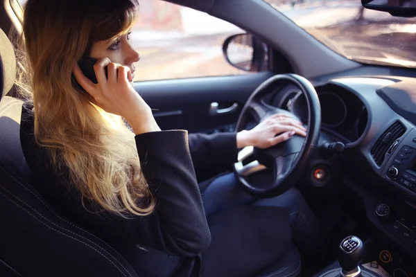 Meisje besturen van de auto en praten van de telefoon — Stockfoto