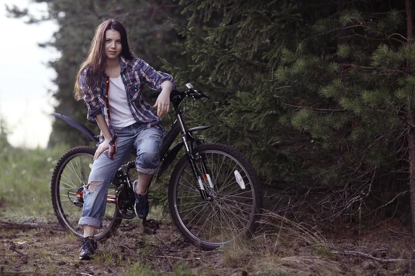 Chica joven en una bicicleta deportiva en un bosque de verano — Foto de Stock