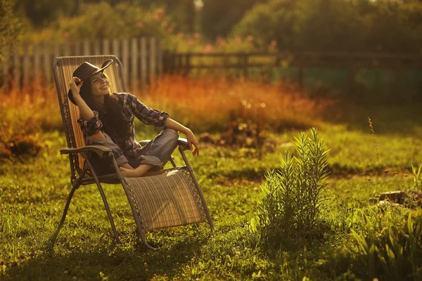 Chica en un sombrero ancho descansando en un sol — Foto de Stock