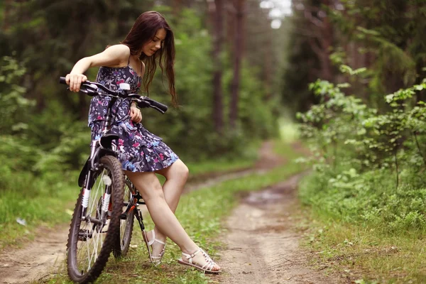 Ung flicka på sport cykel i en sommar skog — Stockfoto