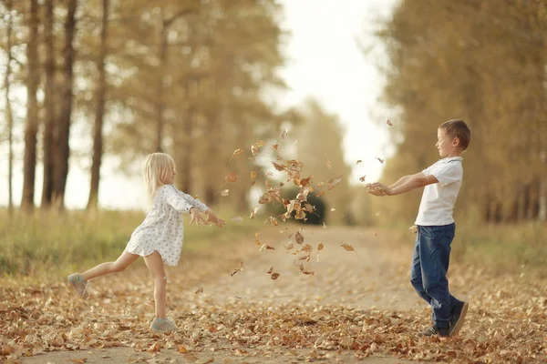 Menino brincando com uma menina no outono no exterior — Fotografia de Stock