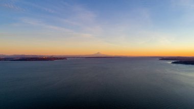 The Puget Sound, Mount Rainier and the Seattle, Washington skyline at sunset from above Bainbridge Island 
