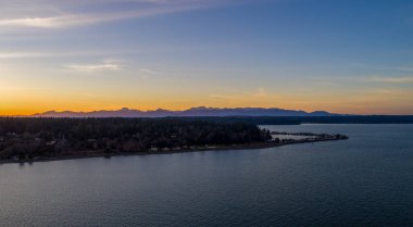 The Puget Sound, Mount Rainier and the Seattle, Washington skyline at sunset from above Bainbridge Island 