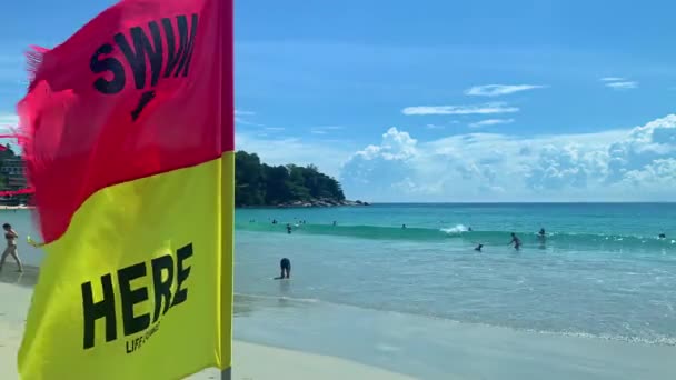 Κολυμπήστε εδώ σημαία στην Ταϊλάνδη παραλία Πουκέτ. άτομα στη θάλασσα με ασφάλεια υπό τον έλεγχο ναυαγοσώστη. — Αρχείο Βίντεο