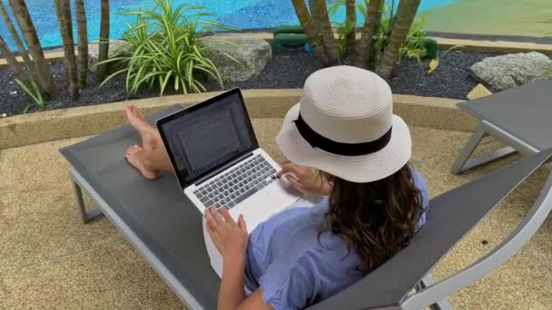 Phuket, Thailandia - Gennaio 2020: giovane donna in forma che scrive un articolo o un documento sul computer portatile in resort con piscina — Video Stock