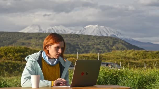 Женщина с ноутбуком работает за столом в туристическом лагере — стоковое видео
