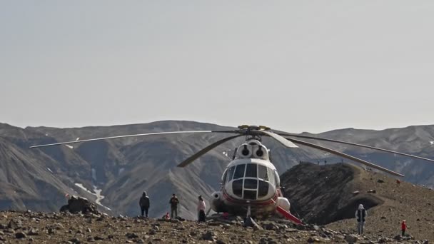 Elicottero e viaggiatori persone sullo sfondo delle montagne Kamchatka durante i viaggi all'aria aperta. — Video Stock