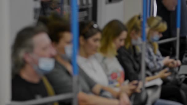 Defokussiertes Video Passagiere sitzen in U-Bahn-Zügen defokussiert auf dem Sitz. Mann und Frau tragen Schutzmaske — Stockvideo