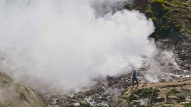 Yürüyüş ve ekolojik turizm kadını gayzerin yanında el sallıyor