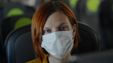 Maskeli kadın havaalanında oturuyor ve içeride gelişini ya da gidişini bekliyor..