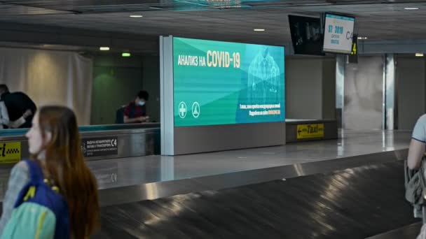 Moskow, Ryssland, 30 augusti 2020, Travelling at pandemic Covid testing add by baggage carousel — Stockvideo