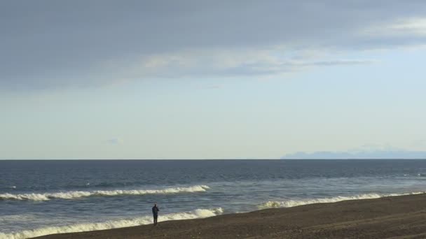 Maravilloso paisaje marino en el día soleado el hombre mira las olas — Vídeo de stock