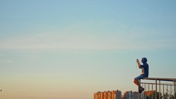 2020年9月10日，俄罗斯伊尔库茨克，人类在夏季日落时在城市拍摄风景照片。在栏杆上坐着，保持聪明 — 图库视频影像