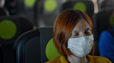 Uçakta maskeli mutlu bir kadın karantina sırasında seyahat ediyor.