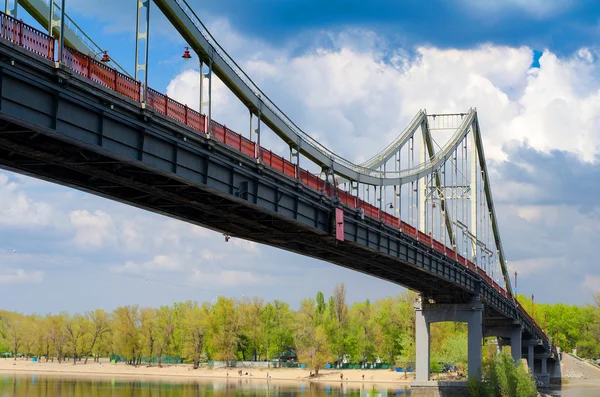 Voetgangers brug over een bewolkte hemel Dnjepr in Kiev — Stockfoto