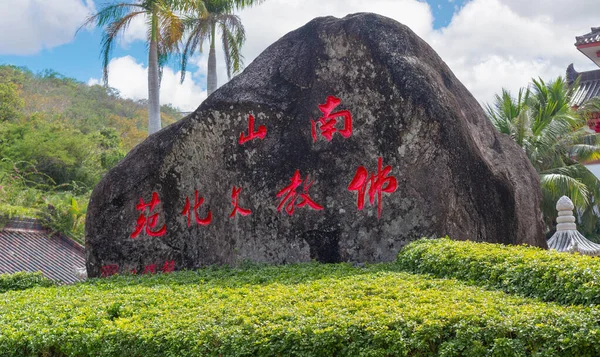 Çin, Hainan Adası, Sanya - 21 Ocak 2020: Nanshan Budizm Kültür Bölgesi 'nin giriş kapısı yakınında kırmızı hiyeroglifli büyük taş. Turistler ve inananlar arasında popüler bir cazibe