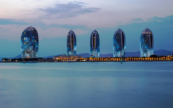 Çin, Sanya - 25 Ocak 2020: Sanya şehrinde ışıklı yapay bir Phoenix adasının alacakaranlık manzarası. Sanya Phoenix Adası 'nda çok renkli binalar Başkan Resort Apartmanı