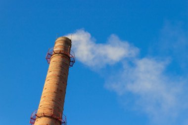 Mavi arka planda beyaz dumanlı eski tuğla baca