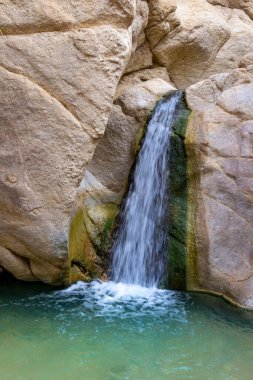 Tunus 'taki Sahra Çölü' nde Nefta yakınlarındaki Chebika vahasındaki kayaların arasında küçük bir şelale. Hareket bulanık su