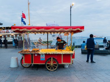 İstanbul, Türkiye - 7 Ekim 2019: Eminonu 'da İskele Yolu' nda kavrulmuş kestane ve haşlanmış mısır satıcısı. Boğaz 'ın setinin akşam manzarası