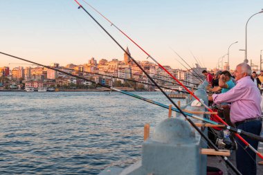 İstanbul, Türkiye - 9 Ekim 2019: İstanbul, Türkiye 'de insanlar gün batımında Galata Köprüsü' nden oltayla balık avlıyor. Popüler hobi ve rahatlatıcı. Seçici odak