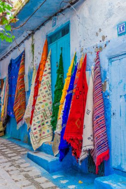 Chefchaouen veya Chaouen kasabası, Fas sokaklarında turistler için renkli el yapımı halı ve yatak örtüleri satmak..