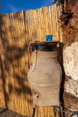 Umumi toprak sürahisi, paspasa saklanmış içme suyu ve Fas 'ta, Tanca' da bir sokakta bağlanmış plastik bardakla. Sıcak bir günde susuzluğunu gidermek için.