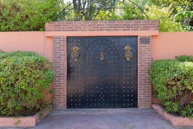 Marakeş, Fas 'taki yeşil bitkiler arasında etnik kapı tokmakları olan kapı.