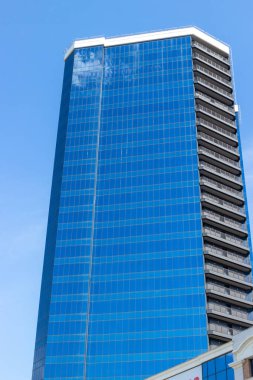 Glass skyscraper building against blue sky. Industrial background