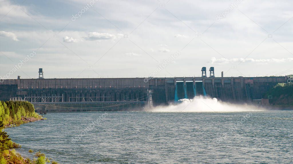 Discharging water to hydroelectric power station in Krasnoyarsk, Russia. Industrial landscape with Krasnoyarsk Dam at sunny day.