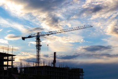 Construction site with crane and building against dramatic sky. Industrial background