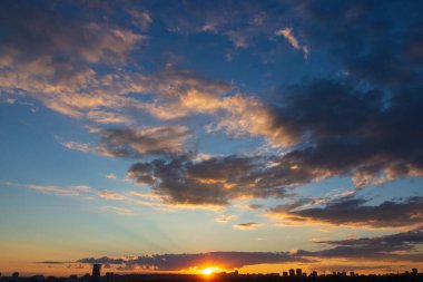 Batan güneşin parlak turuncu ışınları muhteşem bulutların ve gökyüzünün arka planına karşı