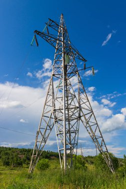 Güneşli yaz gününde mavi gökyüzüne karşı yüksek voltajlı elektrik hattı desteği. Sanayi geçmişi