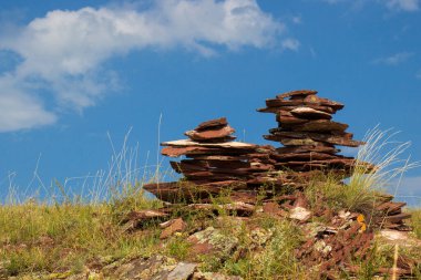 Rusya 'nın Hakassia cumhuriyetindeki Sunduki dağ sırasındaki Devonian kumtaşı ile mavi gökyüzü arka planına karşı taş cairls. Kayaları dengeleme piramidi
