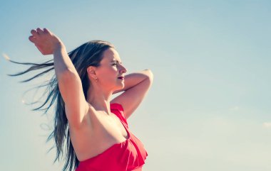 İnce, güzel bir Avrupalı orta yaşlı kadın gökyüzüne karşı kırmızı mayo giymiş olgun bir pantolonla dinlenmek için uçtu. Rüzgar onun uzun koyu saçlarını geliştirir. Boşluğu kopyala