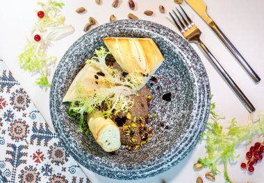 Fıstıklı tavuk ciğeri ezmesi ve beyaz bir masada mermer bir tabakta ekmek. Üst görünüm