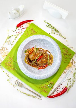 Yeşil bir masa örtüsü üzerinde mermer gri bir tabakta hecelenmiş sığır eti yanakları. Dekorasyon. Üst görünüm