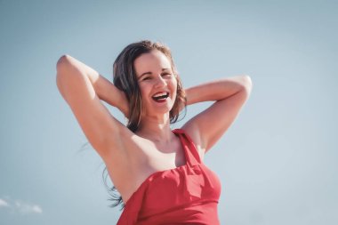 İnce, güzel, Avrupalı orta yaşlı bir kadın gökyüzüne karşı kırmızı mayo giymiş olgun bir pantolonla dinlenmek için uçtu..