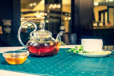 Bal ve taze nane yapraklarıyla sıcak ve bulanık bir arka planı olan cam çaydanlıkta sıcak yeşil çay. Kafede çay ile servis edilir.