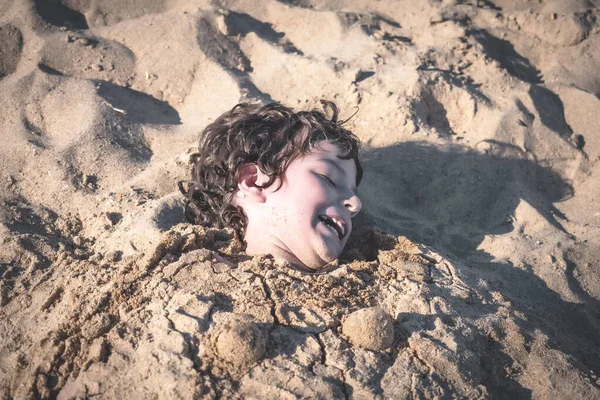 Bambino Giace Sulla Spiaggia Sepolto Nella Sabbia Ragazzo Bruna Ridente — Foto Stock