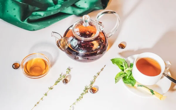 蜂蜜と新鮮なミントの葉と暖かいぼやけた背景を持つガラスティーポットの芳香族ホット緑茶 カフェでお茶とテーブルを提供 — ストック写真