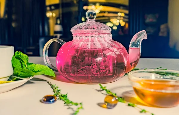 紅茶のケトルが立ち上がり カフェの白いテーブルの上にカップが置かれました テーブルの上にピンクティーと蜂蜜 — ストック写真