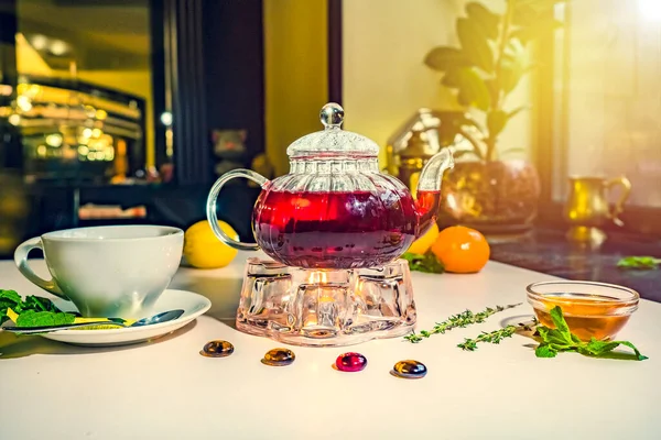 Red fruit tea with rose leaves. Foam tea with spices on the table in a cafe. Kettle warmer