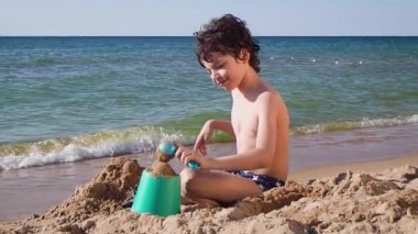 Delikanlı deniz kenarında kumlarda oynuyor.