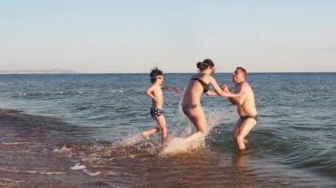 Baba ve çocukları denizde oynuyorlar. 