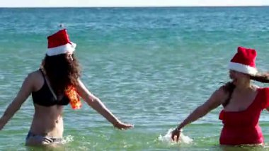 Anne ve kız Noel Baba 'nın Şapkaları' nda eğleniyor, denize su sıçratıyorlar Yeni Yıl kutlamalarında.