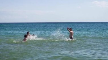 Üç kişilik aile denizde eğleniyor.